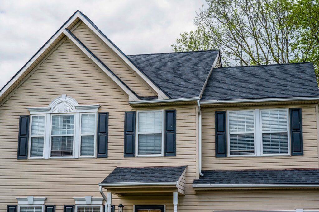 Completed roofing, siding, and gutter services featuring beige siding on a residential home