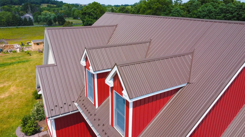 Tan metal roof installed on a red home, part of our roofing, siding, and gutter services
