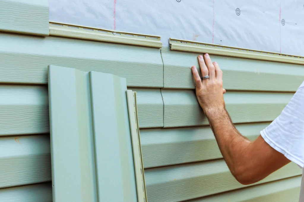 Worker installing siding panels on a home, representing siding services in Martinsburg and Hagerstown